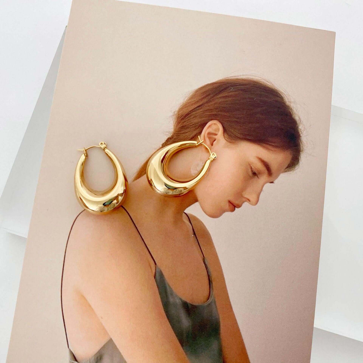 Stainless steel hollow hoop earrings for women displayed next to a model with a soft, elegant hairstyle.