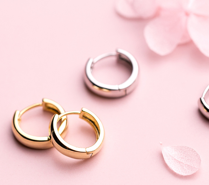 S925 silver round hoop earrings in gold and silver on pink background with flower petals.