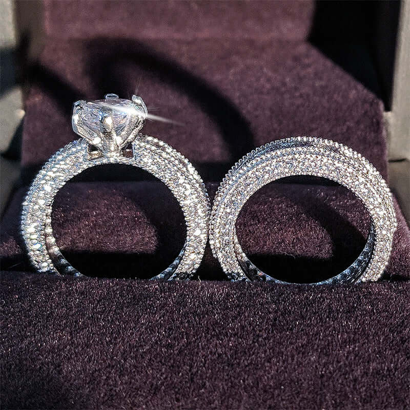 Two 925 sterling silver engagement rings with sparkling diamonds on a dark velvet background.
