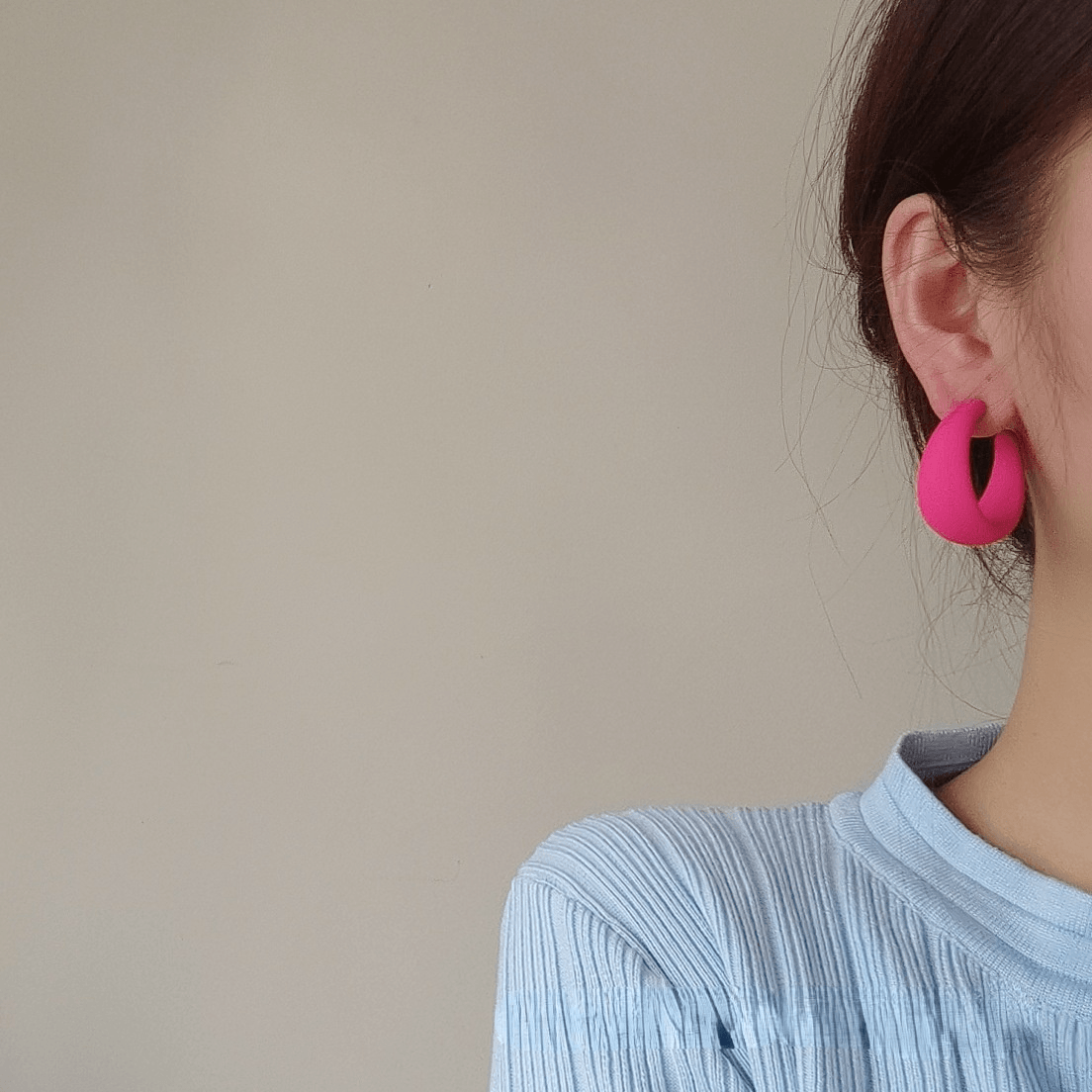 Woman wearing vibrant pink candy color earrings for women, showcasing style and charm.