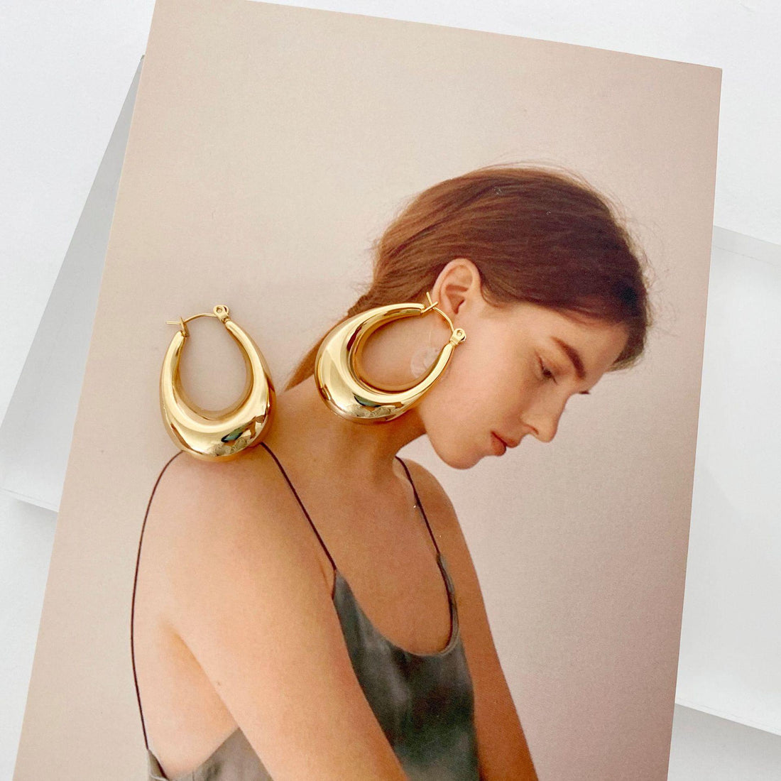 Stainless steel hollow hoop earrings for women displayed next to a model with a soft, elegant hairstyle.