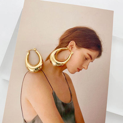 Stainless steel hollow hoop earrings for women displayed next to a model with a soft, elegant hairstyle.
