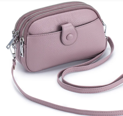 New leather fashion mobile phone bag in soft pink hue with multiple zippers and adjustable strap, perfect for daily use.