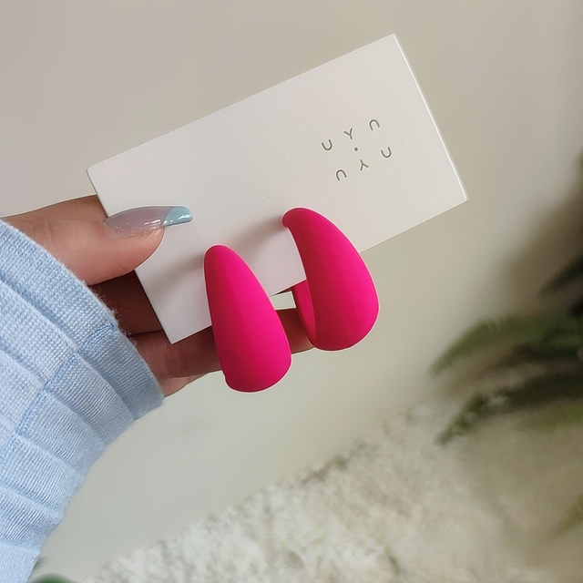 Candy color earrings for women featuring bright pink teardrop design held by a hand, stylish accessory for any occasion.