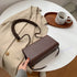 Fashion Messenger Bag - One-Shoulder Small Square Bag in brown with braided strap on a beige coat.
