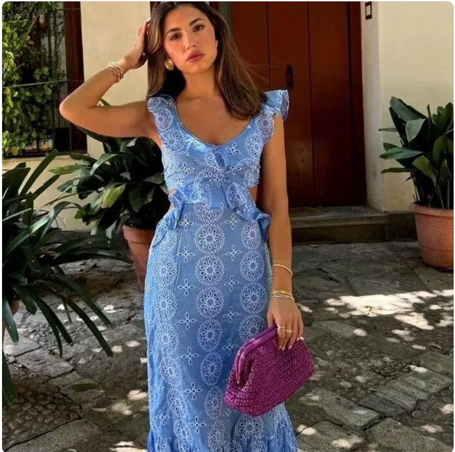 Elegant woman in embroidered midi dress with floral pattern, holding a purple bag, showcasing summer fashion style.