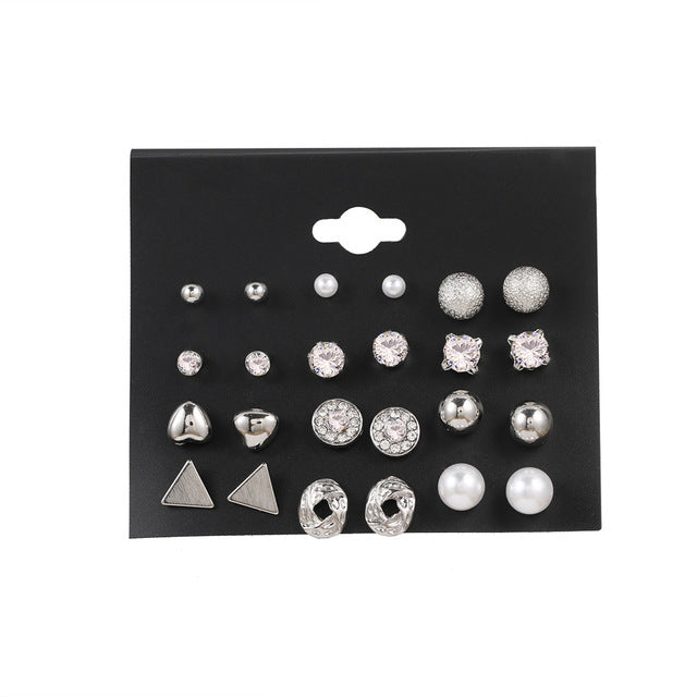 12 pairs of star and moon diamond earrings set featuring silver and sparkling designs on a black card.