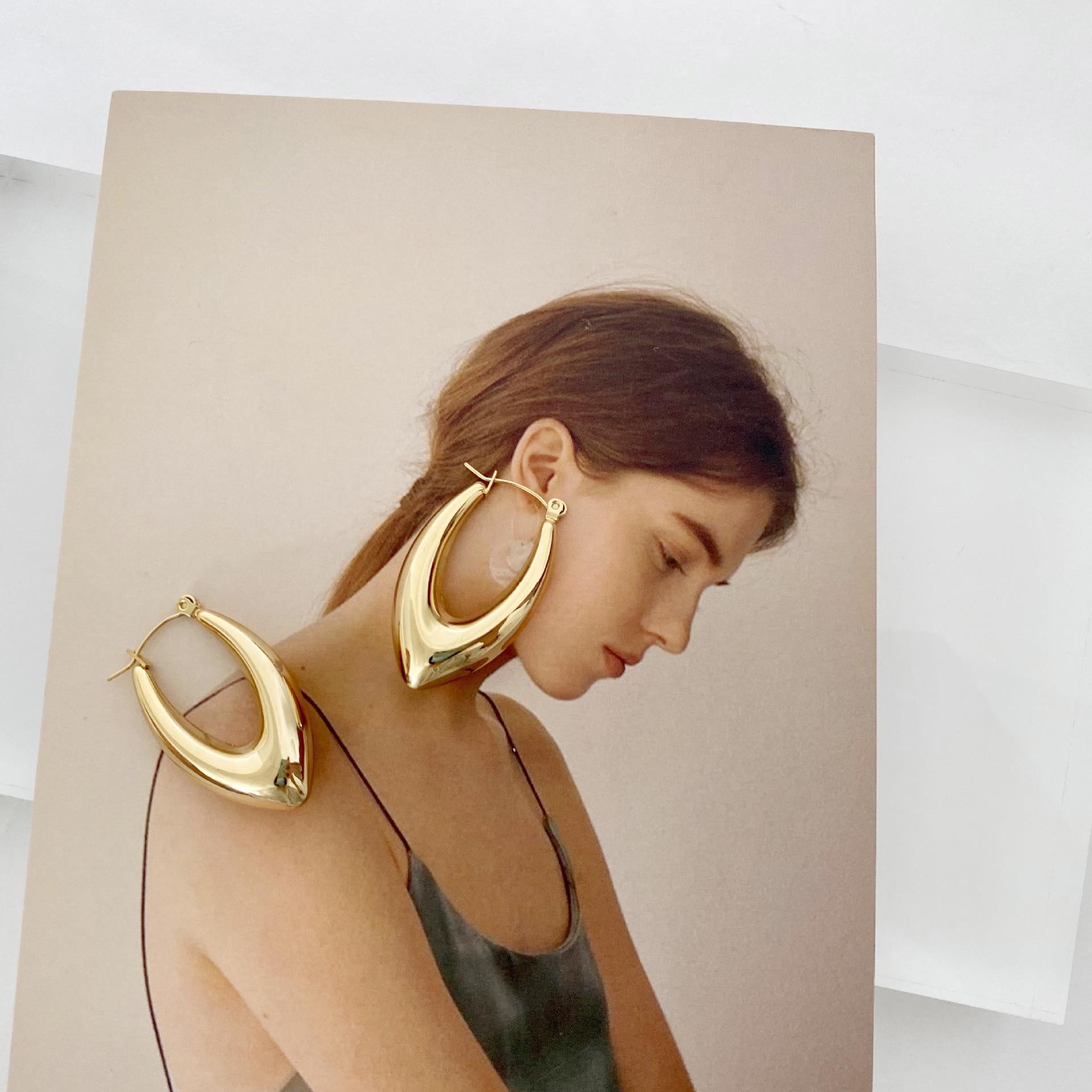 Stainless steel hollow hoop earrings displayed with a model wearing them, showcasing modern geometry and elegance.