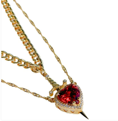 Gold heart and sword necklace set featuring a red crystal pendant and chain design.