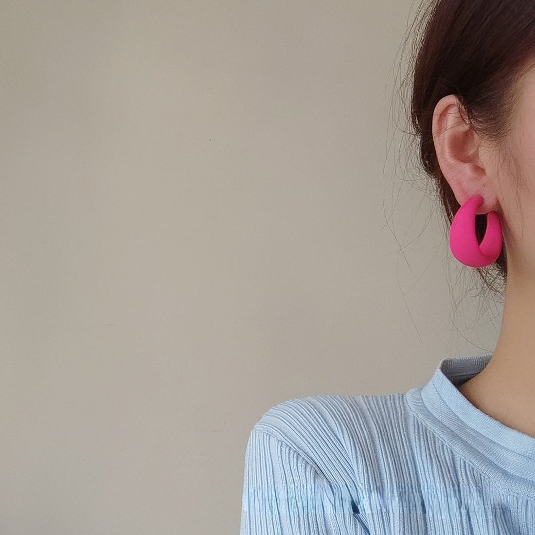 Woman wearing vibrant pink candy color earrings for women, showcasing style and charm.