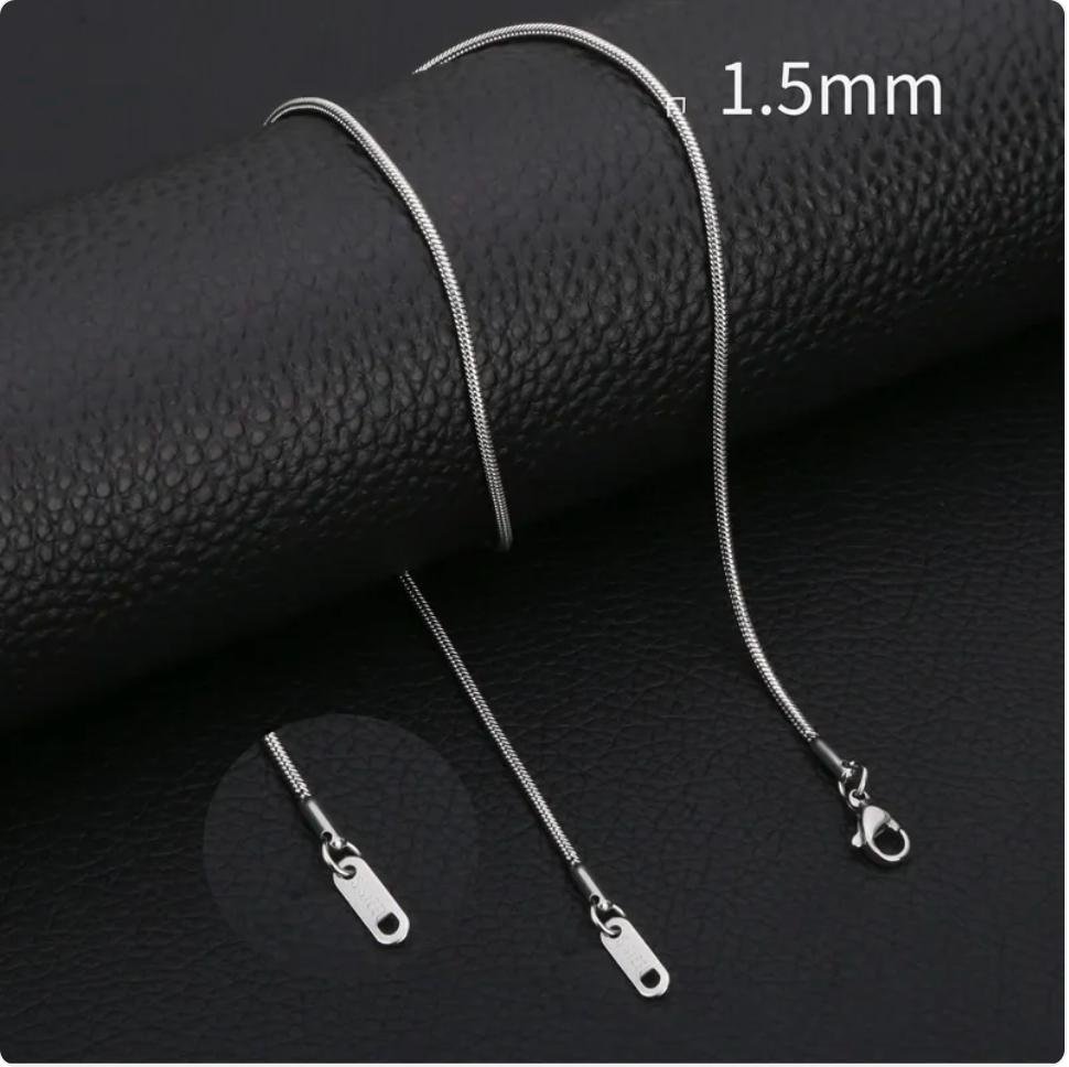 Minimalist stainless steel snake chain necklace on a black leather surface, featuring a 1.5mm width and smooth finish.