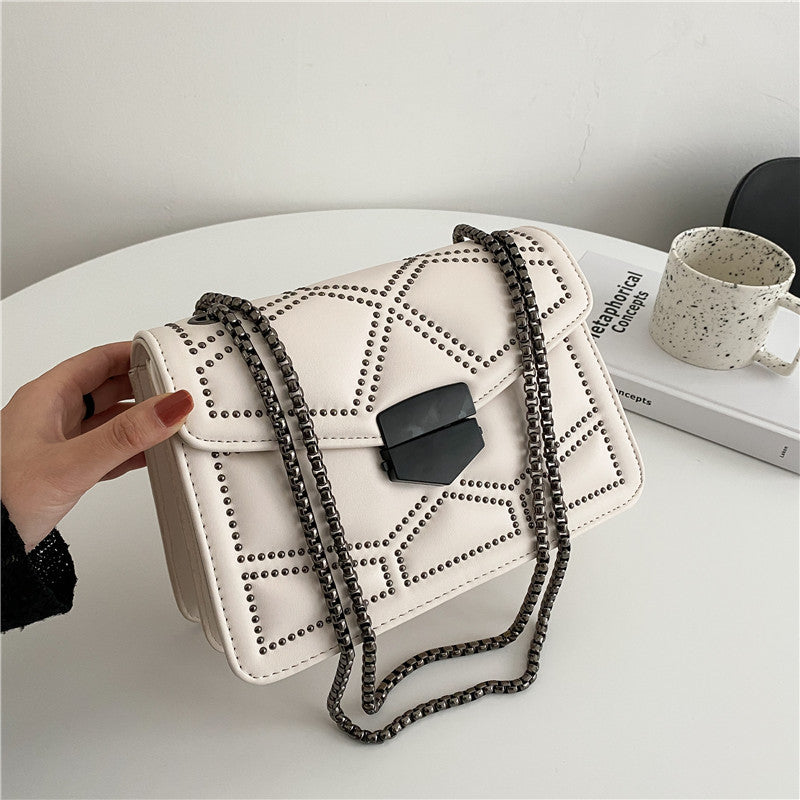 Black chain shoulder messenger bag for women displayed with intricate detail and lock closure on a table.