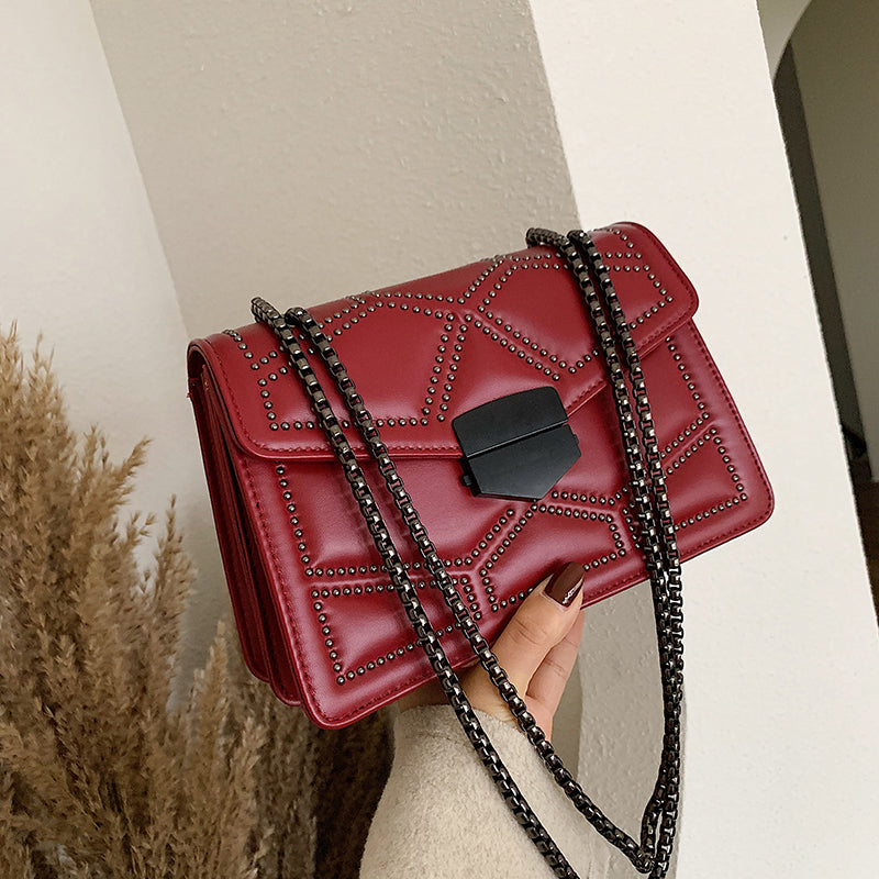 Black chain shoulder messenger bag for women in red, featuring a stylish lock closure and studded design.